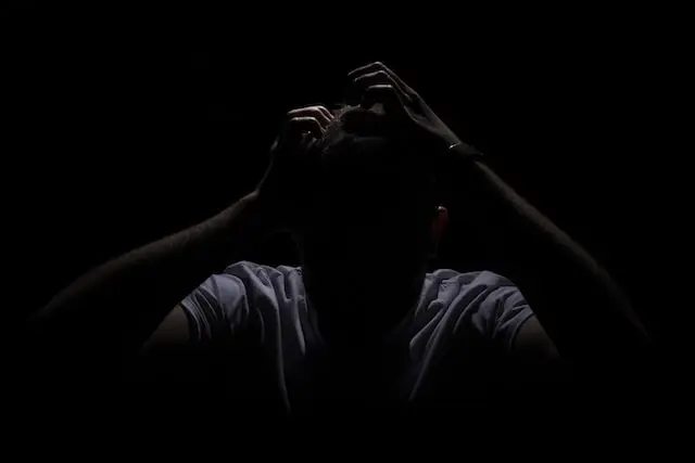 Man in darkness, scared, panicking, holding head because of async void problems